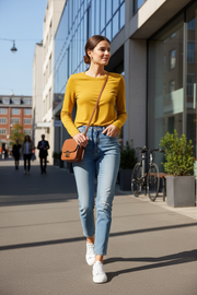 Woman wearing mustard yellow long-sleeve t-shirt in urban setting