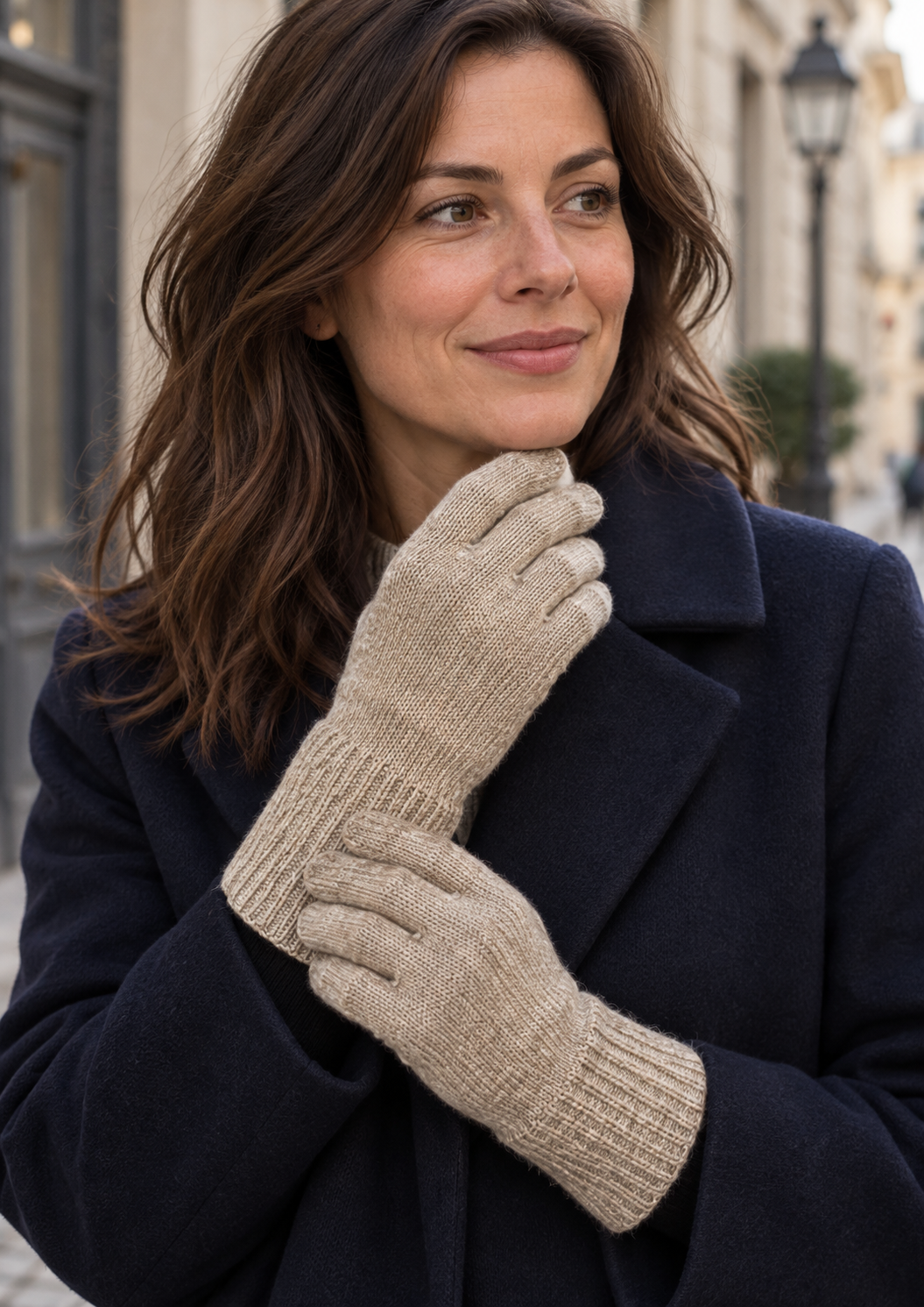 Model wearing beige s.Oliver knitted gloves with a navy coat on a city street