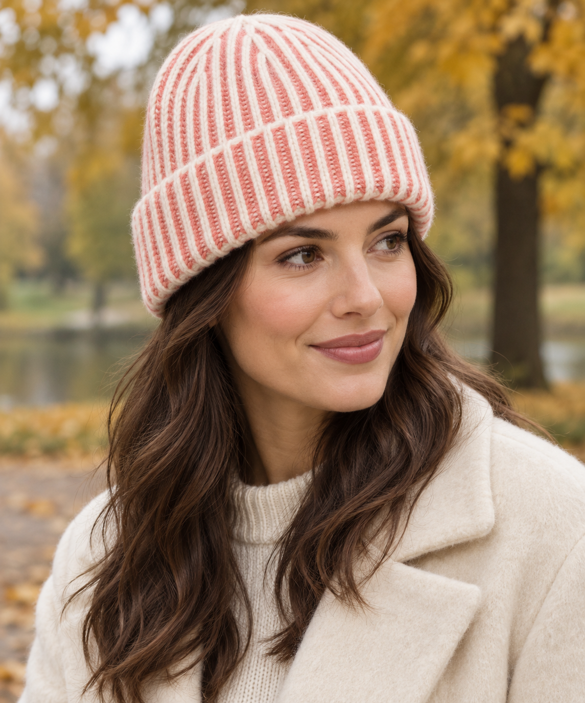 Woman wearing an s.Oliver papaya and cream knitted beanie with a cream coat in an autumn park